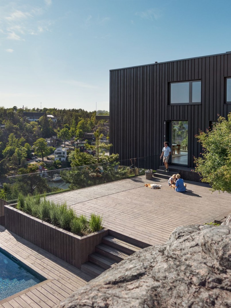 Moderne tumeda fassaadiga maja puidust terrassi ja basseiniga