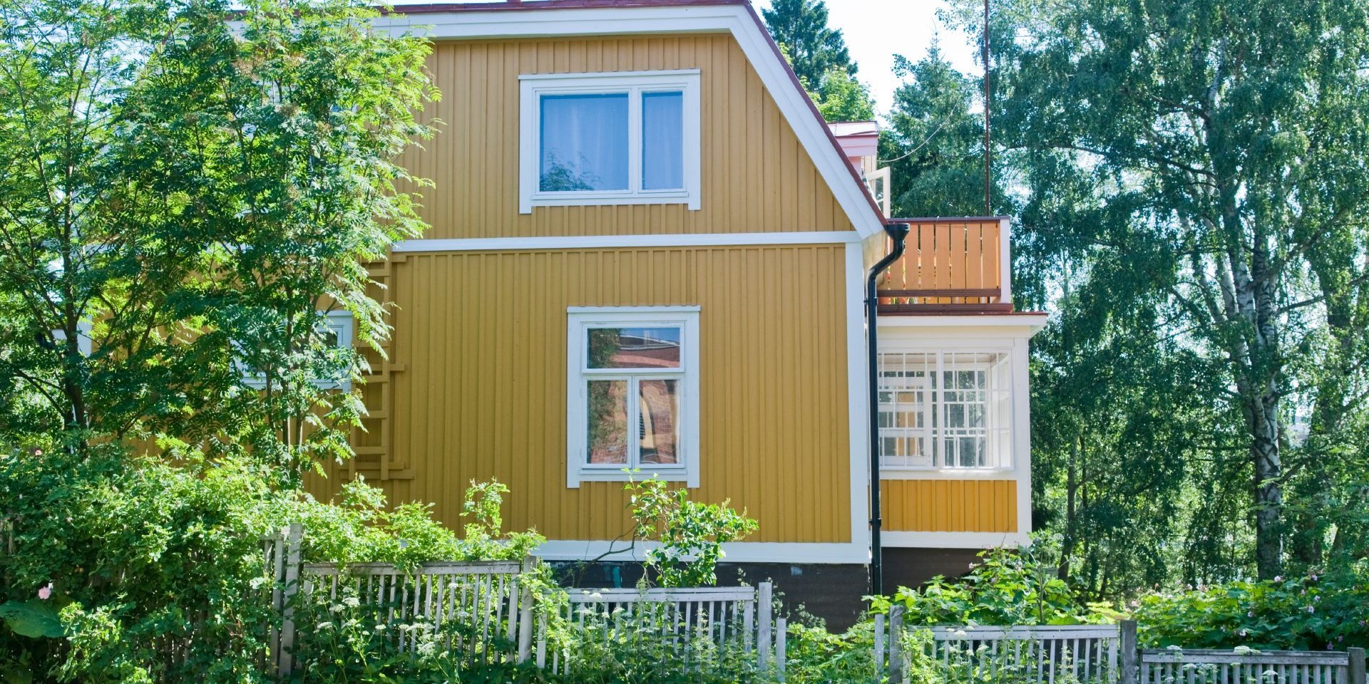 traditional yellow wooden house surrounded by trees