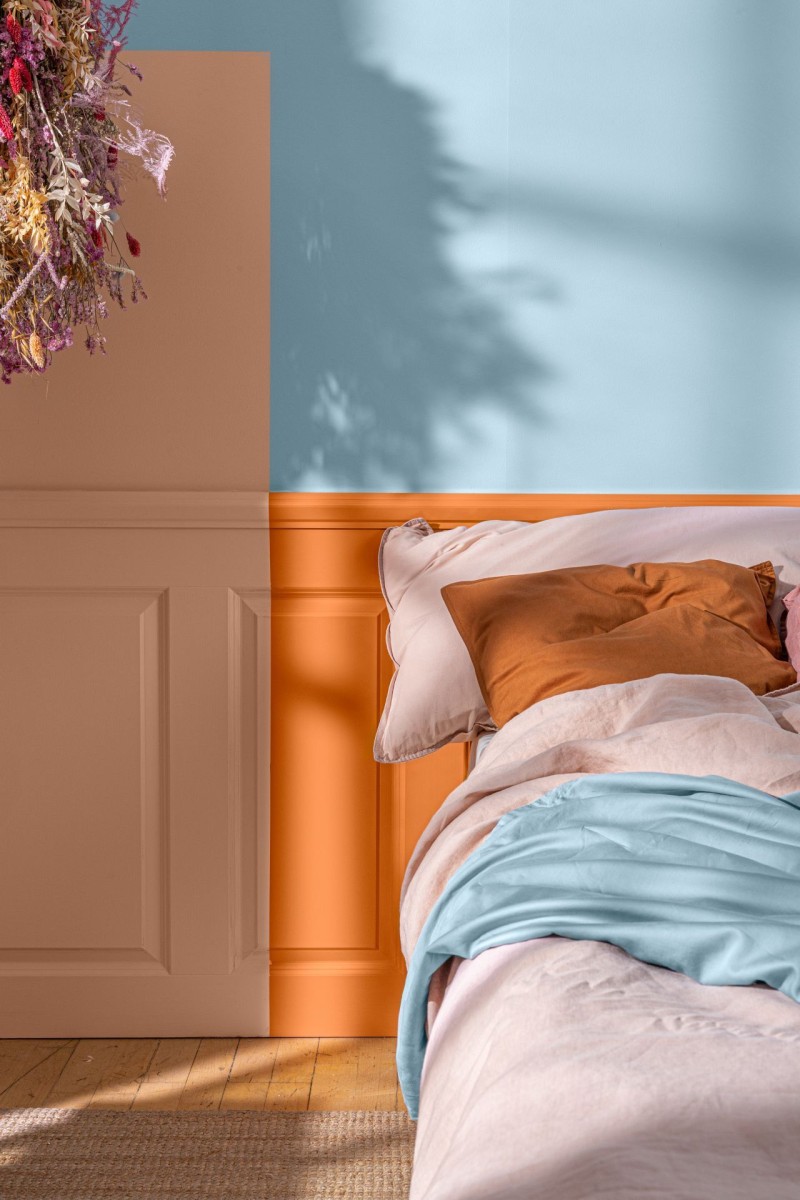 Magamistuba siniseks värvitud seinaga ja erinevad oranžikad toonid voodipeatsis